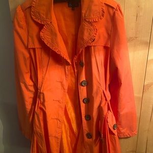 Orange trench coat with ruffle detail.